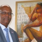 Minister di Hustisia Dennis Richardson den su ofisina dilanti di un pintura di un di su artistanan lokal favorito – Ras Mosera – potrèt: Today/Hilbert Haar